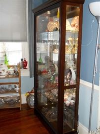 large lighted glass and wood curio cabinet filled with treasures.