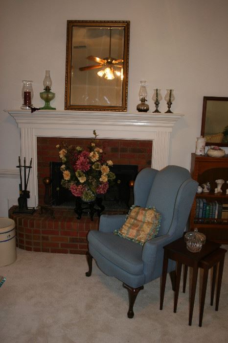 Large silk floral arrangement, vintage mirror, vintage 10 crock, blue wing chair, nesting tables