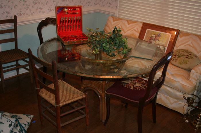 Large glass top table on Rattan base, Brass & Wood Dessert cutlery set, 2 primitive chairs, w carved/needlepoint chairs