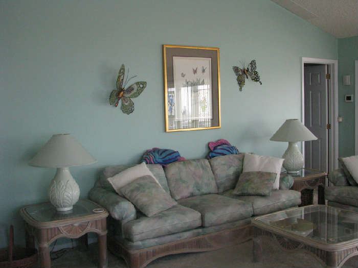 Living room sofa with wall hangings, end tables with lamps and a coffee table. Many other pictures, wall hanging, outboard motor, tools and collectibles. 