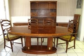 Oval Dining Room Suite showing the Table's Dual Column Base w/leaf shown on the right wall. There are 4 Side and 2 Arm Chairs. Pictured in the background is an open Hutch and 2 Lowboy 3-Drawer Chest. All sold separately.