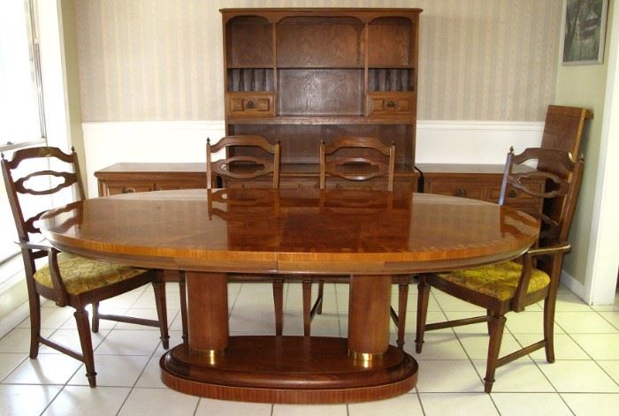 Oval Dining Room Suite showing the Table's Dual Column Base w/leaf shown on the right wall.  There are 4 Side and 2 Arm Chairs.  Pictured in the background is an open Hutch and 2 Lowboy 3-Drawer Chest.  All sold separately.
