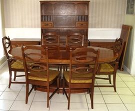 Oval Dining Room Table on Dual Column Base w/leaf shown on the right wall. There are 4 Side and 2 Arm Chairs. Pictured in the background is an open Hutch and 2 Lowboy 3-Drawer Chest. All sold separately.