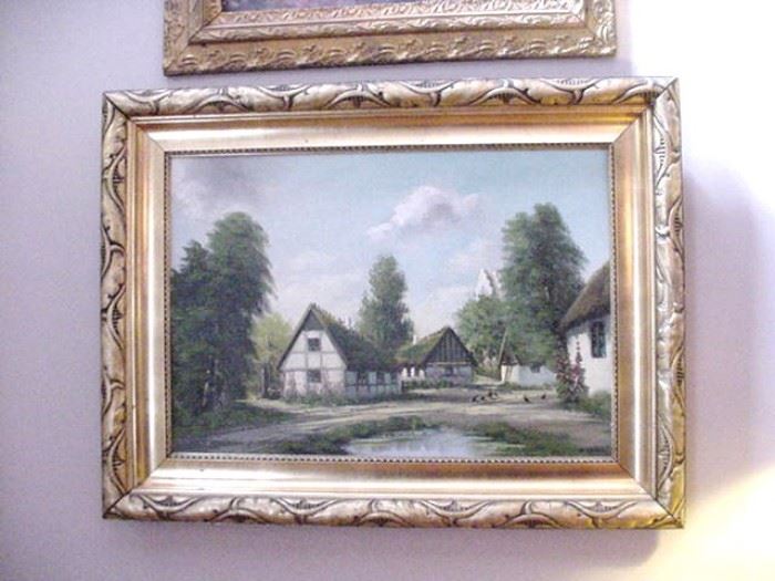 Oil on canvas of thatched roof houses surrounding a pond 