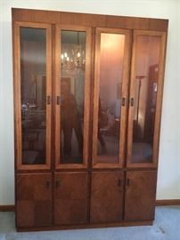 Mid Century "Founders" lighted walnut china/curio cabinet--glass shelves and doors above with solid doors, shelves and drawers below. Oval dining table and rolling server/bar also available.