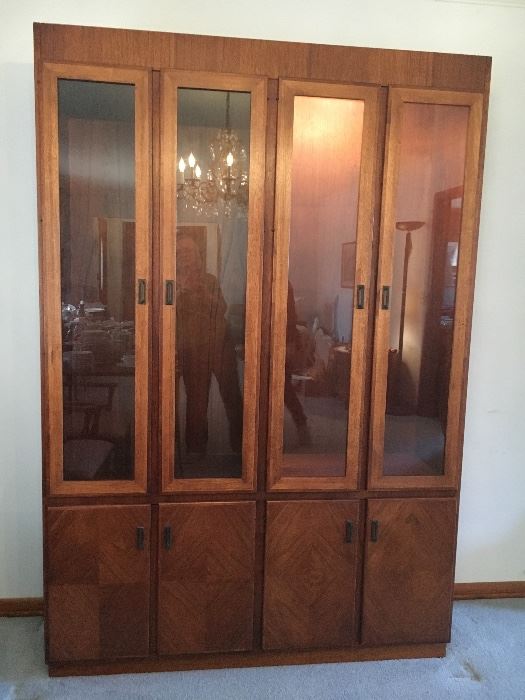 Mid Century "Founders" lighted walnut china/curio cabinet--glass shelves and doors above with solid doors, shelves and drawers below. Oval dining table and rolling server/bar also available.