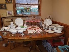Oak pedestal table with chairs, Corelle dishes, Gibson dishes, stainless flatware, prescut glass, & more. 