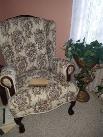 Wing back chair with buttons & wooden claw feet. Silk floral arrangement in resin pitcher.