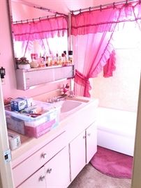 Pretty in pink bathroom with lots of brand new household items and a collection of perfume bottles!