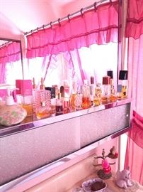 Pretty in pink bathroom with lots of brand new household items and a collection of perfume bottles!