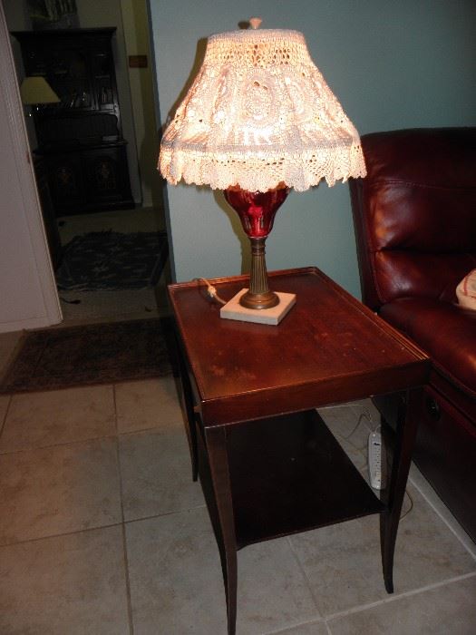 Mahogany side table with top edge, red glass antique lamp with lace shade
