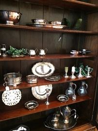 Large selection of silver plate serving pieces in large antique display cabinet