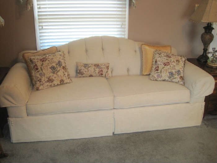 Lovely Candice Olson beige sofa with decorator pillows and buttons on each end of skirt