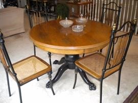 Antique claw foot oak table with black accent and four metal framed chairs with wicker seating