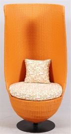 Lot#71, MODERN CONTEMPORARY CHAIR, C1980, H 5' 7", W 30"High back pedestal chair with orange faux wicker style weave with seat cushion and pillow supported by a pedestal ending with a round black metal base. Barrel back rest.