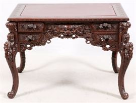 Lot#2231, CHINESE CARVED ROSEWOOD DESK, H 30'', W 48'', D 32''.Having a rectangular top surface surrounded by a Chinese carved meander border above a heavily carved skirt with a dragon mask on each side flanked by two stacked narrow drawers with carved rose design pulls. Contoured bottom edge of skirt. Carved dragon mask side panels. Contoured carved legs with flower and vine designs.