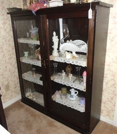 Collection of antique and contemporary opalescent white glass in glass fronted cabinet.