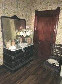 An unattached oversized mirror rests on this ebony-finished mahogany marble-topped dresser. Chairs at right are part of a set.