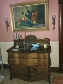 Antique serpentine oak sideboard with carving and wood inlays. This is a very special piece!!
On top are glass and crystal pieces. The vintage cornucopia oil painting is highlighted by two glass and brass candle sconces.