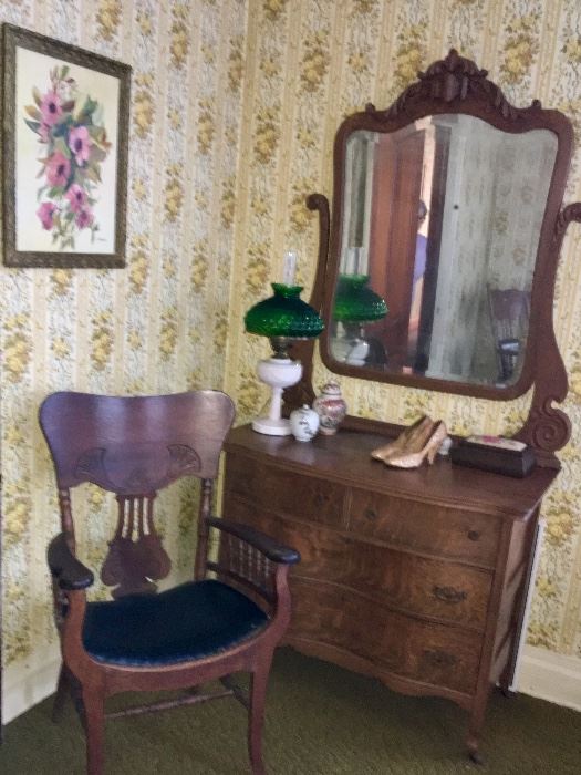 A fine example of an antique serpentine oak dresser with matching attached mirror.  The chair is Victorian-era with ebony leather seat.