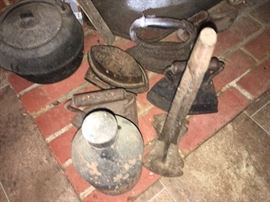 Collection of cast iron pressing irons alongside a cast iron Dutch oven.