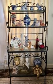 Baker's rack with assorted décor--blue and white ceramics, cat figurines, brass animals and more.