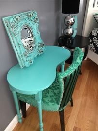 Small aqua-painted vanity with emerald green upholstered chair and shabby-chic vintage, ornate, painted aqua mirror.