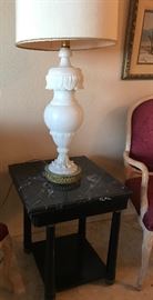 There are a pair of large carved alabaster table lamps; black marble top end table