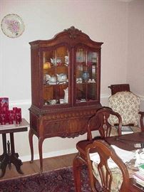 China cabinet on cabriole legs; matching dining table in foreground and one of the arm chairs against wall with side chairs at table