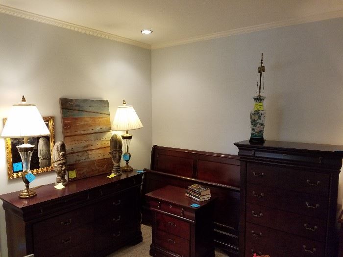 Queen bedroom suite which includes sleigh bed, upright dresser, nightstand, and triple dresser with mirror.