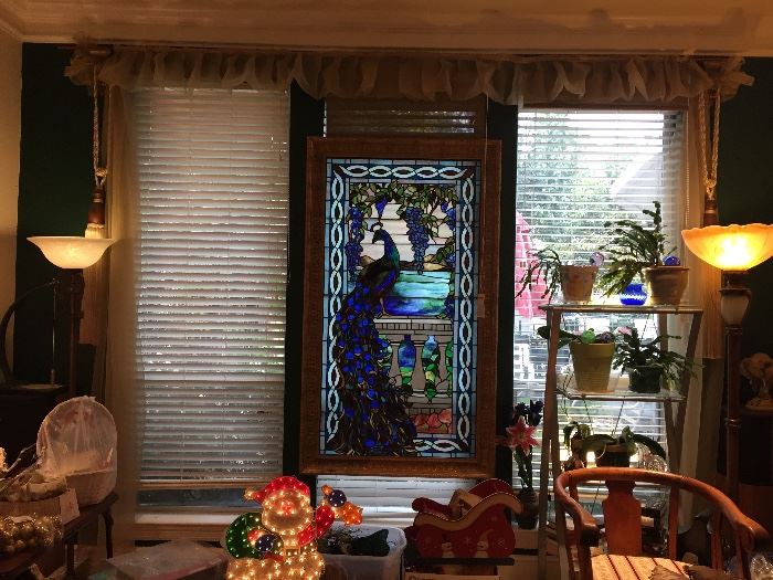 View of Main Room with Tiffany window in center flanked by two art nouveau floor lamps with beautiful glass globes and bronze like columns. Santa Xmas decoration lights up! Metal and glass etagere holding plants. 