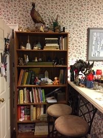Bookcase in kitchen with cookbooks; two wrought iron bar stools 