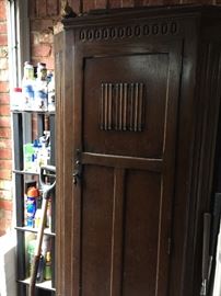 Tall narrow wooden cabinet with fine metal latch and interior mirror 