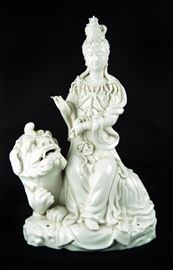 16. PORCELAIN GUAN YIN ON QILING瓷觀音造像     A finely molded Blanc de chine sculpture of Guan Yin seated on a qiling with one hand held in mudra and the other with a Buddhist implement.                             H:11 1/2in W:6 3/4in
