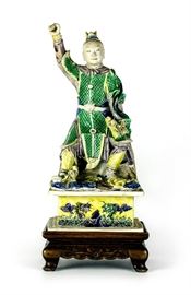 15. QING DYNASTY (1616-1912) SU SANCAI FIGURE 清(1616-1912)素三彩人物造像Made of porcelain; finely colored and carved; modeled after a Chinese soldier; with a wood stand. H: 13 in

