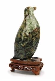 46. JADEITE PENGUIN翡翠雕企鵝狀擺件Mottled in dark greens and cool browns, this jadeite penguin comes with a customized wooden stand. Beak of the figurine has been chipped. 25g H:6 1/2in W:3in
BEAK BROKE