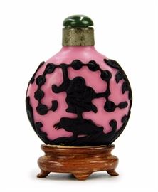 56. PINK AND BLACK GLASS SNUFF玻璃胎鼻煙壺Rounded in body, this snuff bottle has a pink base layered with black carvings depicting a boy on a frog holding a string of coins. H:3in