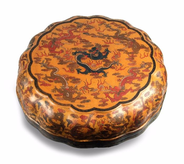 73. ROUND LACQUER DRAGON BOX龍紋漆雕蓋盒With lobed edges, this lacquer box is halved, with black leiwan bands around the edges and covered entirely in curling dragons. H: 7in W: 18.5in