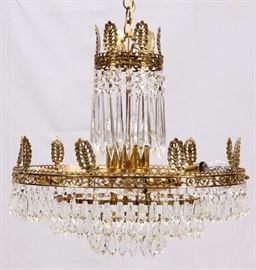 Lot#39, NINE LIGHT CRYSTAL AND GILT BRASS CHANDELIER, LATE 20TH C, H 24", DIA 24"Nine light chandelier having a gilt brass pierced design frame of vines and blossoms with attached leaf form finials at the top the frame. All of which attach to a center shaft  which is surrounded by long vertical prisms surrounding three lights. The lower portion consists of a larger diameter pierced design frame which also has vines and blossoms and leaf form finials and six horizontal lights mounted inside the frame. Crystal beads and tear drop prisms are suspended from this larger frame. Two more smaller diameter frames are tiered down from the larger frame at the bottom also with suspended beads and prisms.