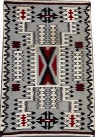Lot#51, NAVAJO KLAGETOH STYLE HAND WOVEN WOOL MAT, W 24", L 36"Having a gray field with geometric feather designs in white, red and black.