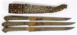 Lot#340, PERSIAN TRIPLE THROWING DAGGER SET, INSIDE ONE ENGRAVED SILVER SHEATH. 3 separate daggers with engraved hilts and single edged blades 6 inches long with gold damaine and Arabic script with a lion head at tip of scabbard. The case is closed and is inset with three rows of gemstones and coral bead at the handle top.  Estate of Frederick C. Matthaei, Jr.