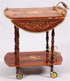 Lot#354, ITALIAN INLAYED TEA WAGON  OPENS TO ROUND H 31", W 16", L 26"Having a round top with drop leaves and pierced, gilt metal gallery on the top and scroll form and turned wood push handle. Inlays of flowers and acanthus leaf designs. Turned spindle legs with casters. Lower stretcher shelf also with inlays. Gilt metal wire frame to secure bottles on lower shelf.