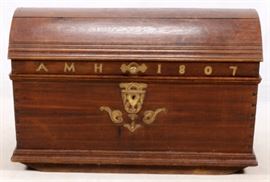 Lot#1067, CONTINENTAL DOME-TOP OAK AND MAHOGANY TRUNK, 19TH C., H 30", W 22", L 46"Continental oak and mahogany dome-top trunk. Late 18th century. Decorated with hand-cut brass monogram reading "AMH" and dated 1807. The lock decorated with incised and pierced strap work with scrolled foliate details. With wrought iron side handles. Accompanied with a key. Lock functions.