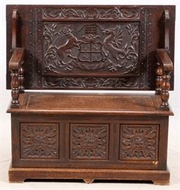 Lot#1069, CARVED OAK MONK'S BENCH, LATE 19TH/EARLY 20TH C., H 30", W 20", L 41"English oak monk's bench table. Late 19th or early 20th century. The top having foliated-carved banding, folding back to form a bench with a left top seat. The back rest carved with the House of Beaufort coat-of-arms and motto "Mutare vel timere spemo" ("I scorn to change or to fear"), raised above lift-top bench opening to storage, and with foliate-carved panels to sides.
