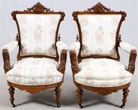 Lot#1099, AMERICAN RENAISSANCE REVIVAL WALNUT PARLOR CHAIRS, C. 1870, PAIR. In the manner of John Jeliff (1813-1893), each has a shaped, upholstered back with a medallion crest above an upholstered seat flanked by padded open arms with female mask supports, raised on turned legs ending in casters. From the estate of Edward P. Frohlich, Grosse Pointe Farms.
