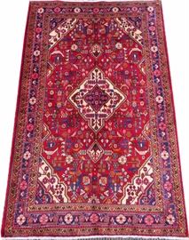 Lot#1190, PERSIAN SAROUK WOOL CARPET, 1990-00, 5' 5" X 3' 6"A red ground with cream colored canted corners; decorated with stylized foliage in shades of blue, orange, and pink.