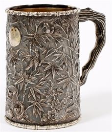 Lot#1326, CHINESE EXPORT SILVER MUG H 3 1/2" DIA 2 1/2"A Chinese export silver mug, likely manufactured by Sunshing. Having repousse bamboo and floral decoration, and branch handle. With impressed maker's mark to underside.