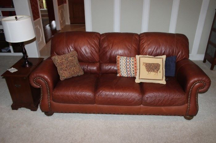 brown leather sofa with nail-head trim and pillows