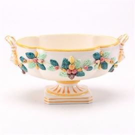 Mid-Century KBNY Italy Decorative Ceramic Centerpiece: A mid-century KBNY Italy decorative ceramic centerpiece bowl. This item features an oval bowl with serpentine yellow edge and two handles to either side. The exterior of the bowl is decorated with applied ceramic leaves and berries. Bowl sits on a pedestal with a cut-corner square base.