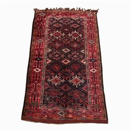 Vintage Hand-Knotted Turkmen Area Rug: A vintage hand-knotted Turkmen area rug. The rug features a central field of large hooked medallions in bright cherry red, saturated merlot, bright blue, white and black, with powder blue and apricot with shades of green. It has a pair of guard borders with a circular pattern in the field colors, and a wide primary border of rectilinear floral and foliate elements, alternating with bisected diamond forms in the same palette. It has double braided and woven overcast edges with a small weft kilim skirt, and long, hand-tied wool fringe in the warp colors. Unmarked.